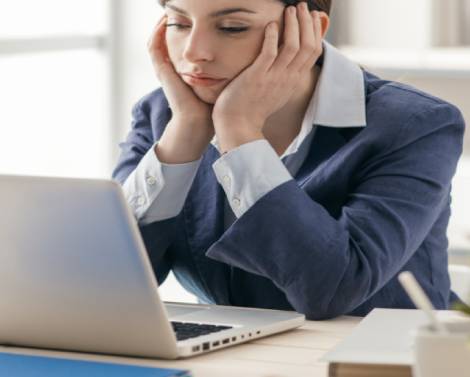 woman with her hands on her face sitting in front of her laptop