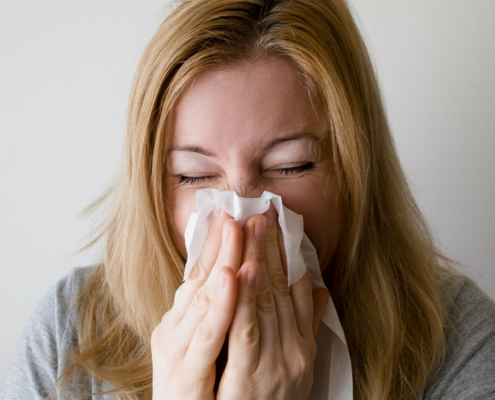 Woman sneezing on tissue