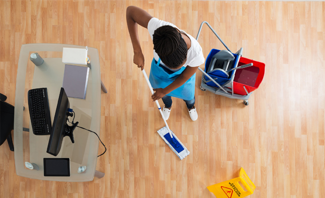 overhead view of staff mopping the office floor with flat mop and putting caution wet floor sign