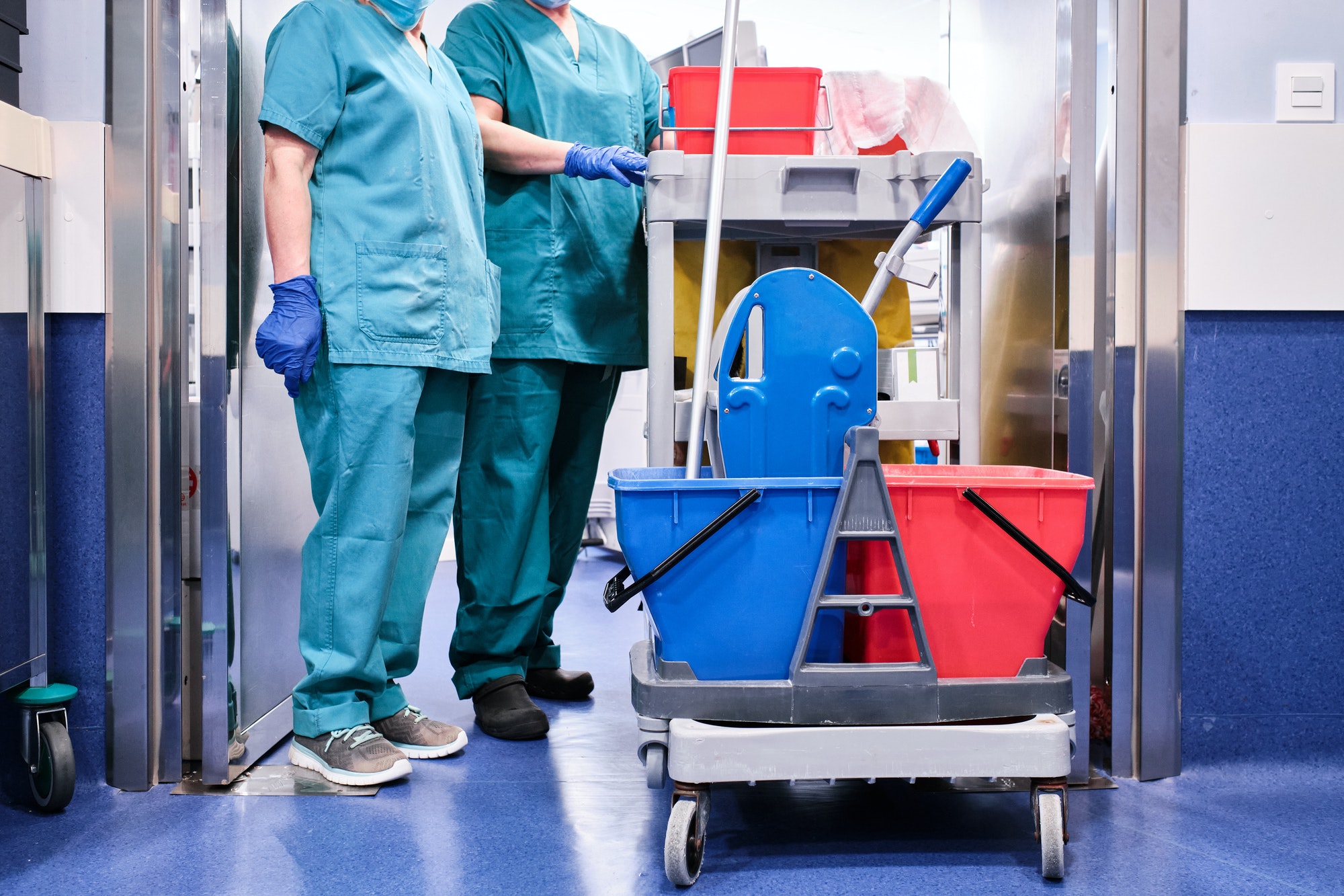 cleaning staff next to a cleaning cart at a hospital