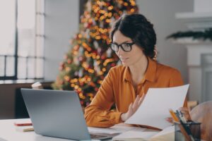 Hispanic business lady in glasses working online in office on Christma
